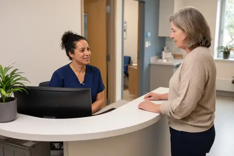 A clinic receptionist helping a patient at the front desk