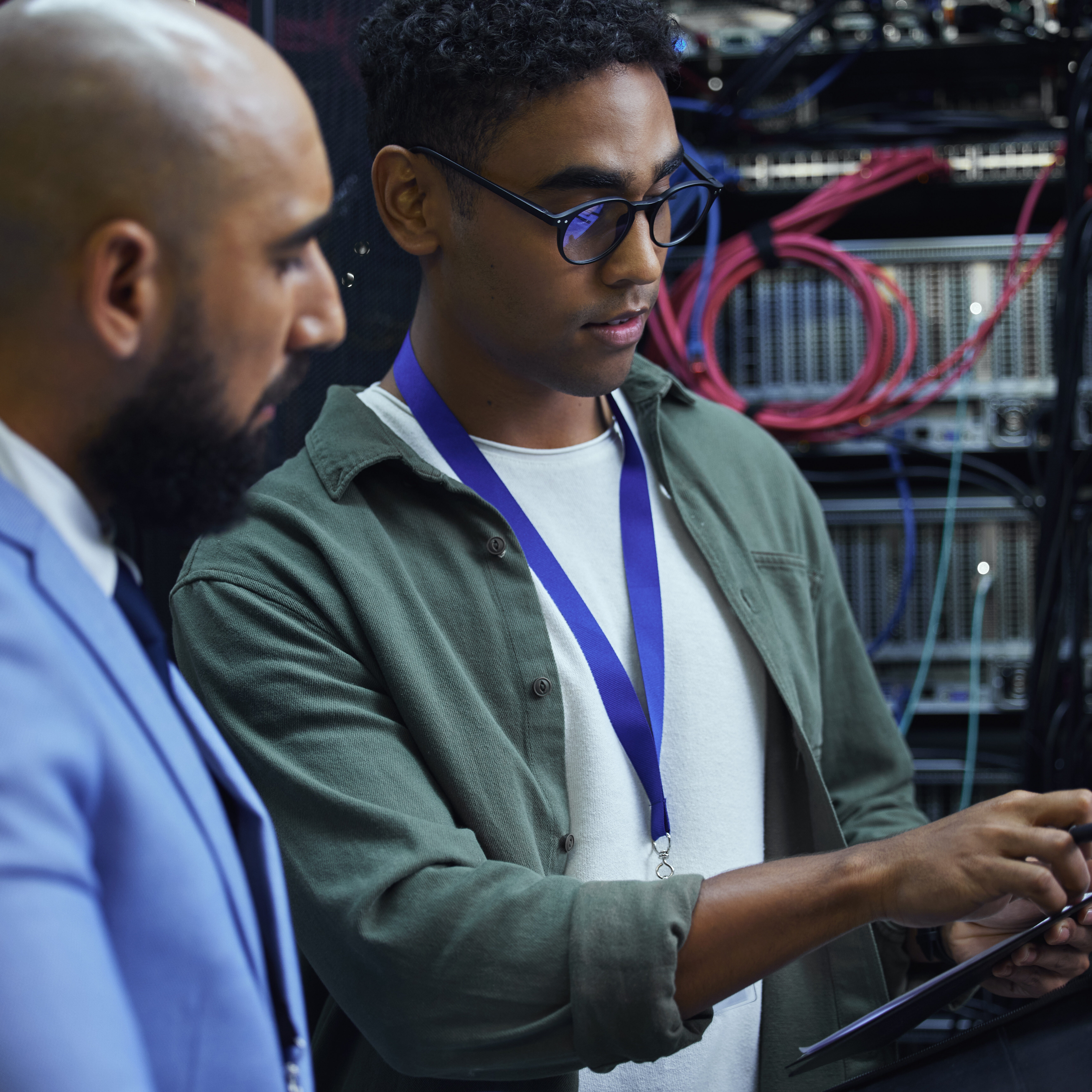 Cropped shot of two male IT support agents working together in a dark network server room.